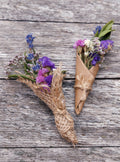 Two small bouquets of wildflowers wrapped in brown paper on a wooden surface